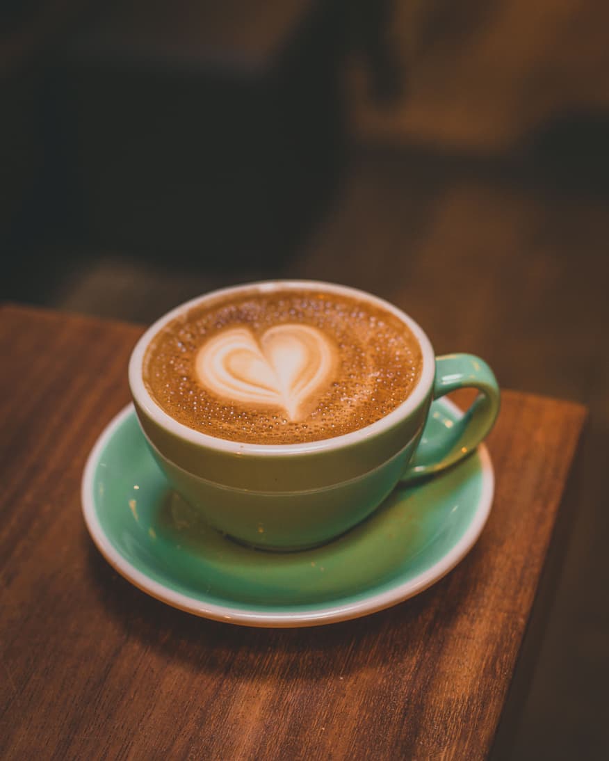 Taza de cafe mediana con un capuccino y un corazon como arte latte