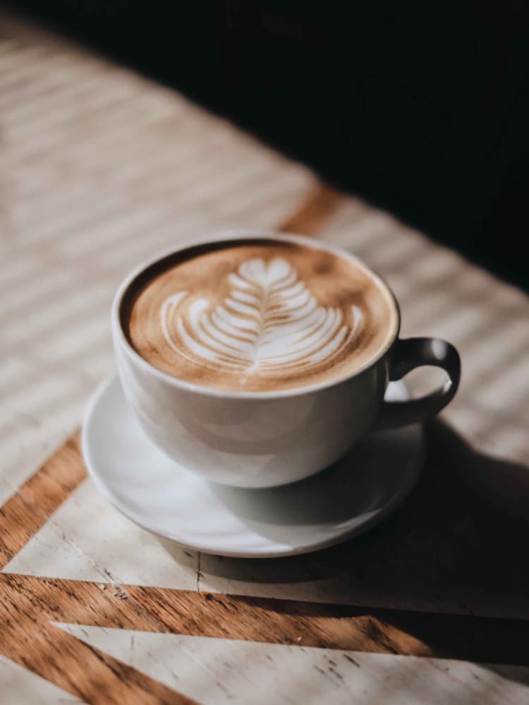 Taza de cafe mediana con un latte y una roseta con corazon como arte latte